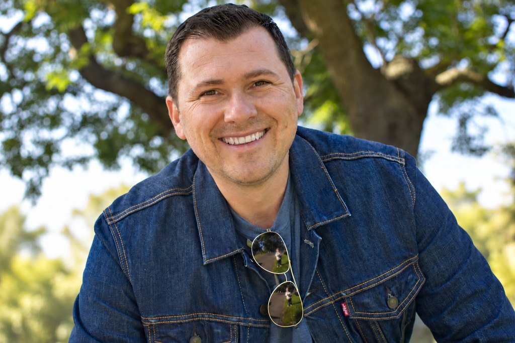 Jevad Huseinbegovic, smiling, in a denim jacket outdoors